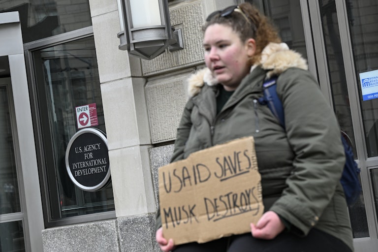 A person holds a protest sign in support of USAID outside the agency building in Washington, D.C.
