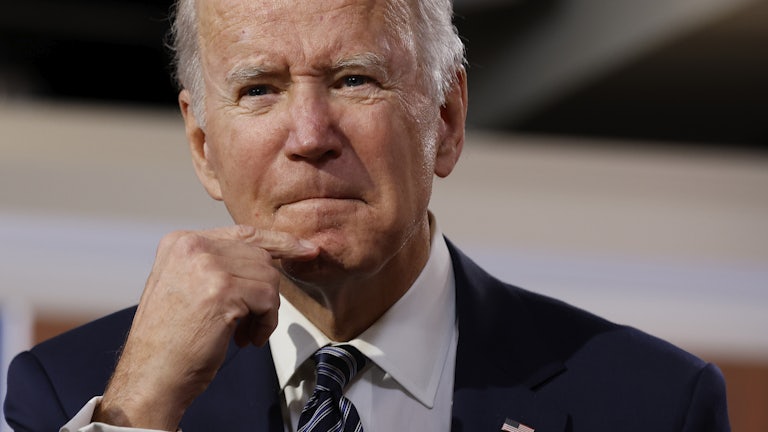 President Joe Biden strokes his chin as he grimaces.