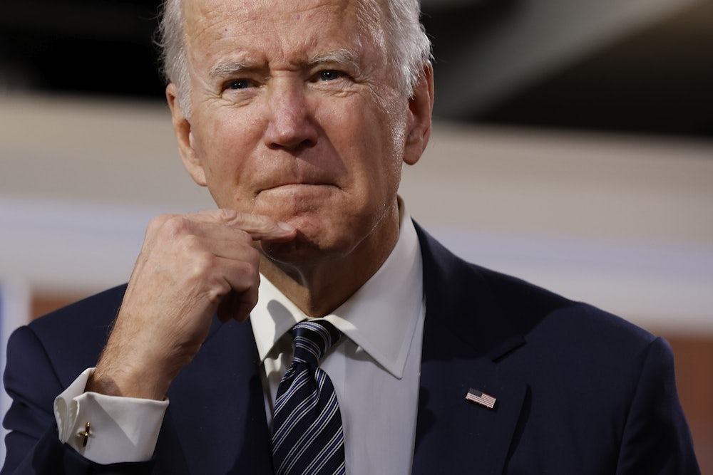 President Joe Biden strokes his chin as he grimaces.