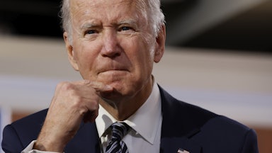 President Joe Biden strokes his chin as he grimaces.
