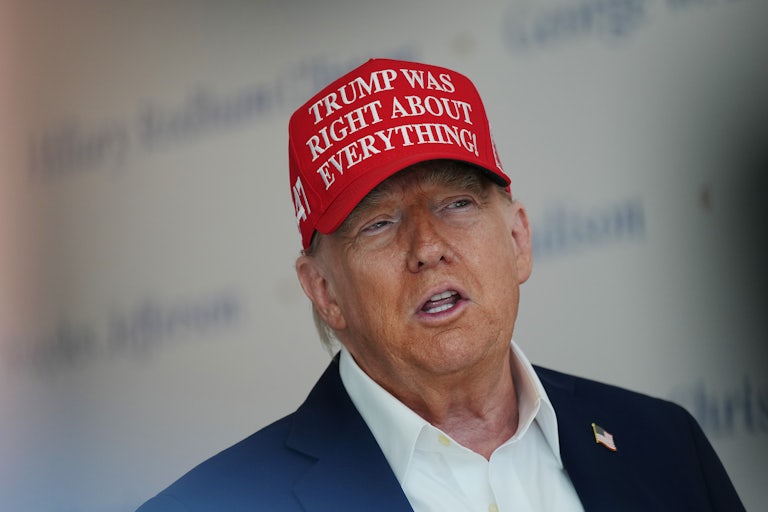 President Donald Trump, wearing a red hat, speaks at a press conference.
