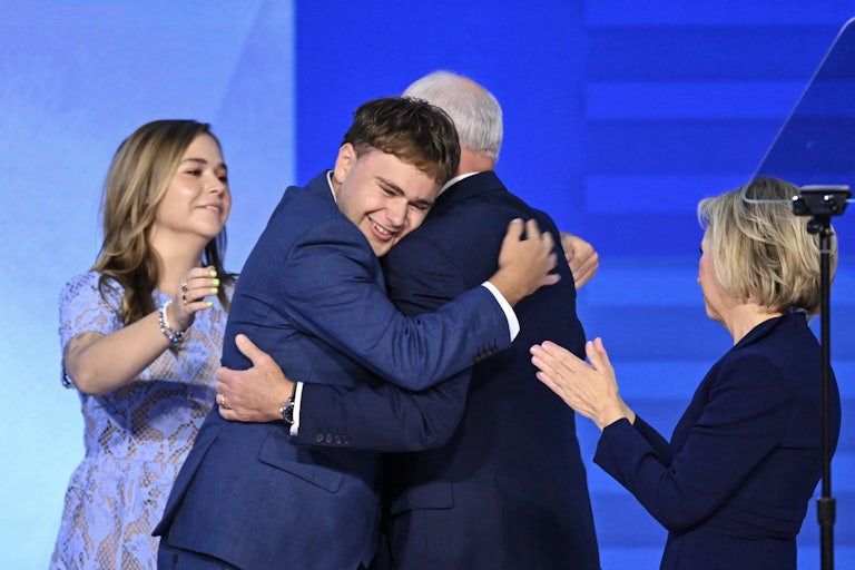 Tim and Gus Walz hug on stage at the Democratic National Convention while Hope and Gwen Walz look on