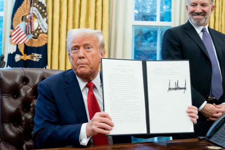 Donald Trump holds up an executive order he just signed in the Oval Office