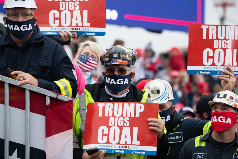 People in hard hats hold signs saying "Trump digs coal."