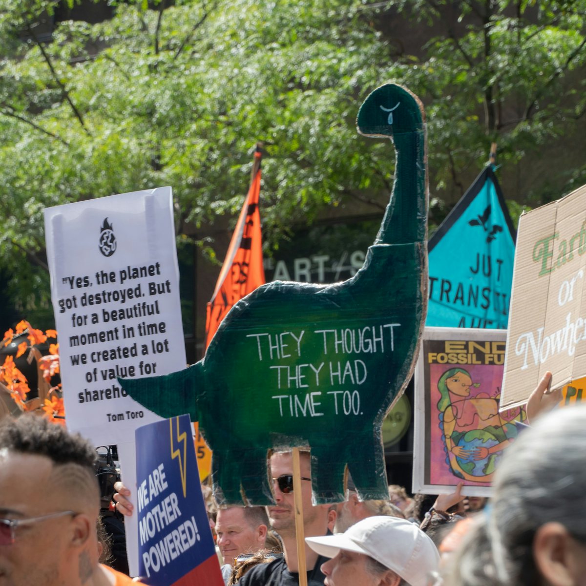 A sign shaped like a dinosaur reads "they thought they had time too."