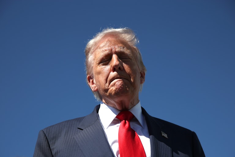 Donald Trump stands with his lips pressed together and his eyes closed