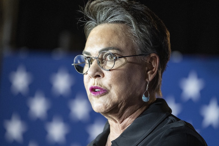 Representative Harriet Hageman speaks with a U.S. flag in the background. She seems distressed or shocked.