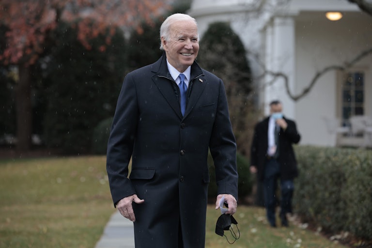 Joe Biden smiles while walking on the White House lawn.