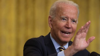 A close up of Joe Biden, holding his hand in front of his face.