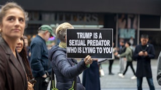 A person holds up a sign that says, "Trump is a sexual predator who is lying to you" during a protest in Times Square