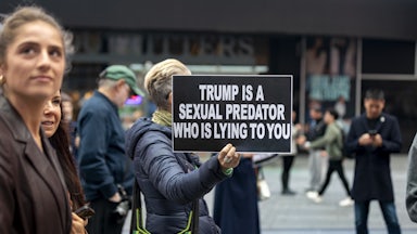 A person holds up a sign that says, "Trump is a sexual predator who is lying to you" during a protest in Times Square