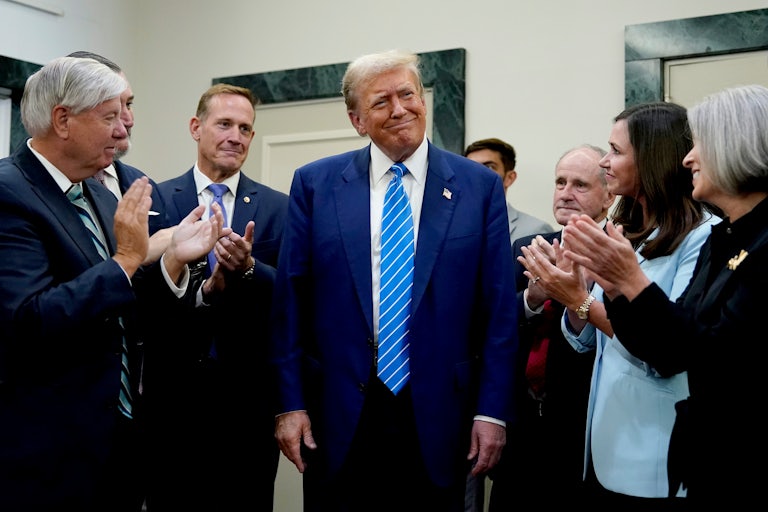 Donald Trump stands in the center as Senate Republicans circle him and clap. Trump smiles smugly.