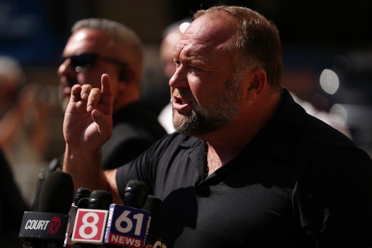 Alex Jones gestures as he speaks to reporters