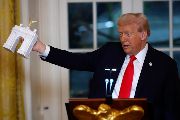 Trump holds a model of his proposed arch