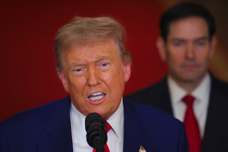 Donald Trump speaks into a microphone while Secretary of State Marco Rubio stands behind him