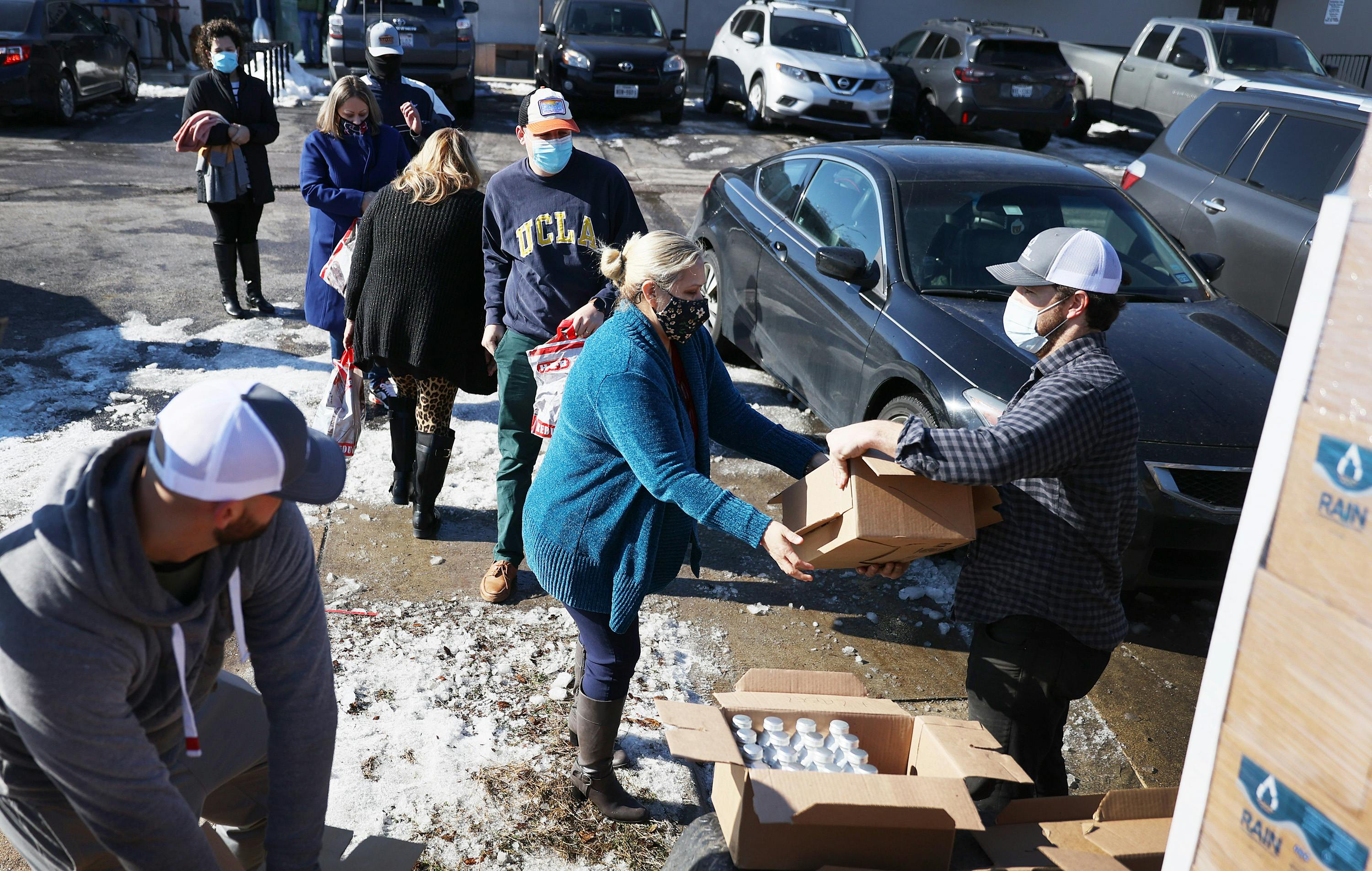 A man gives a package of bottled water to a woman.