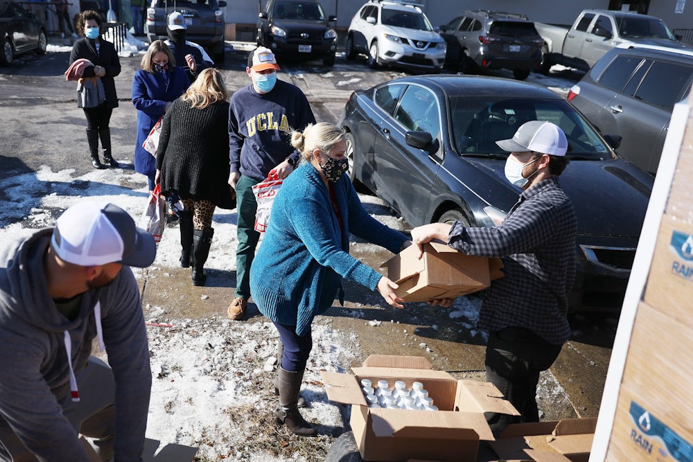 A man gives a package of bottled water to a woman.