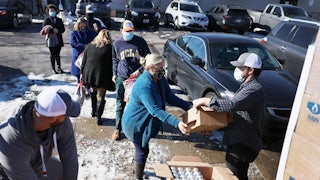 A man gives a package of bottled water to a woman.