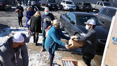 A man gives a package of bottled water to a woman.