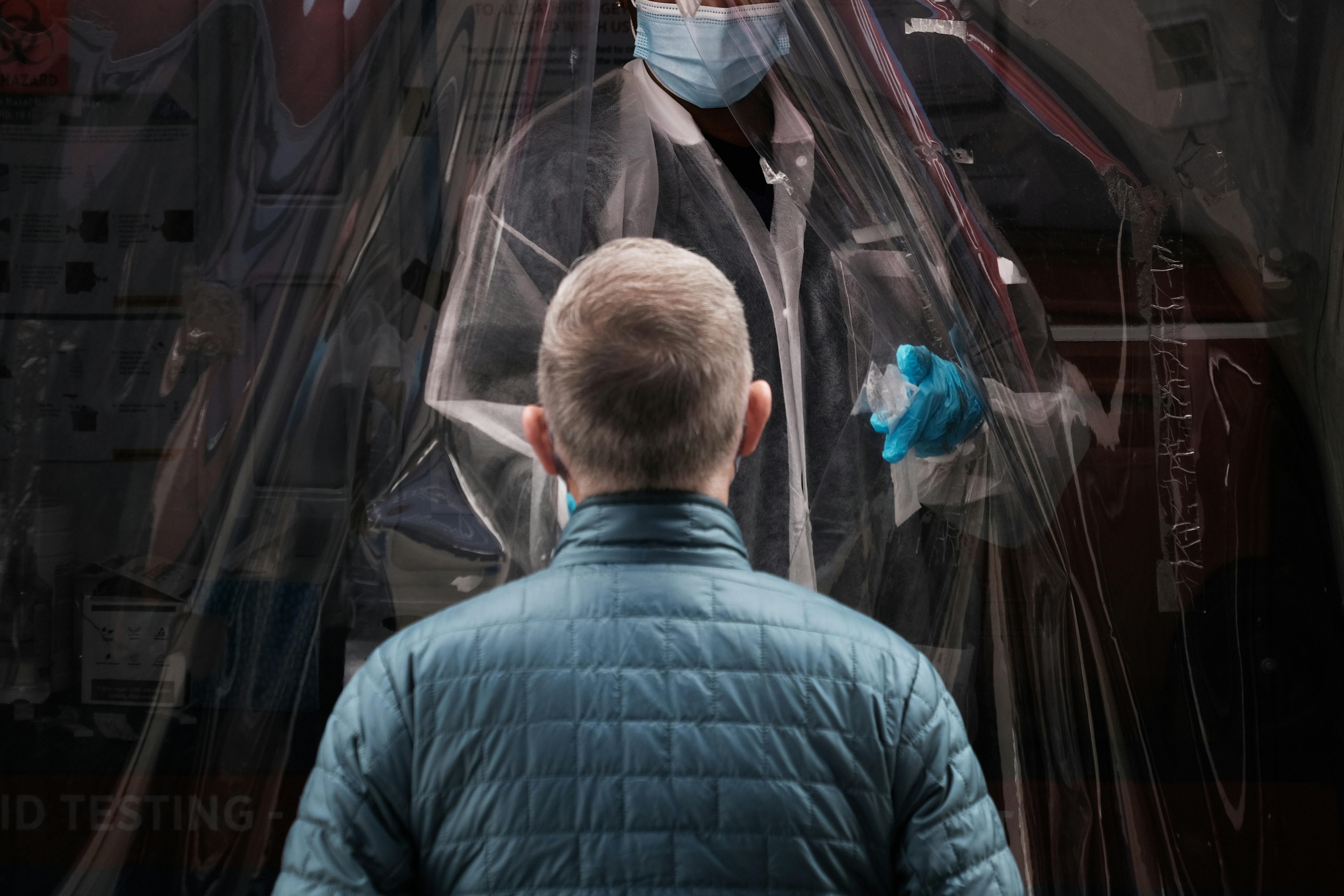 A person stands in front of a medical worker, waiting to be tested.