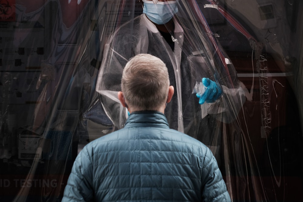 A person stands in front of a medical worker, waiting to be tested.