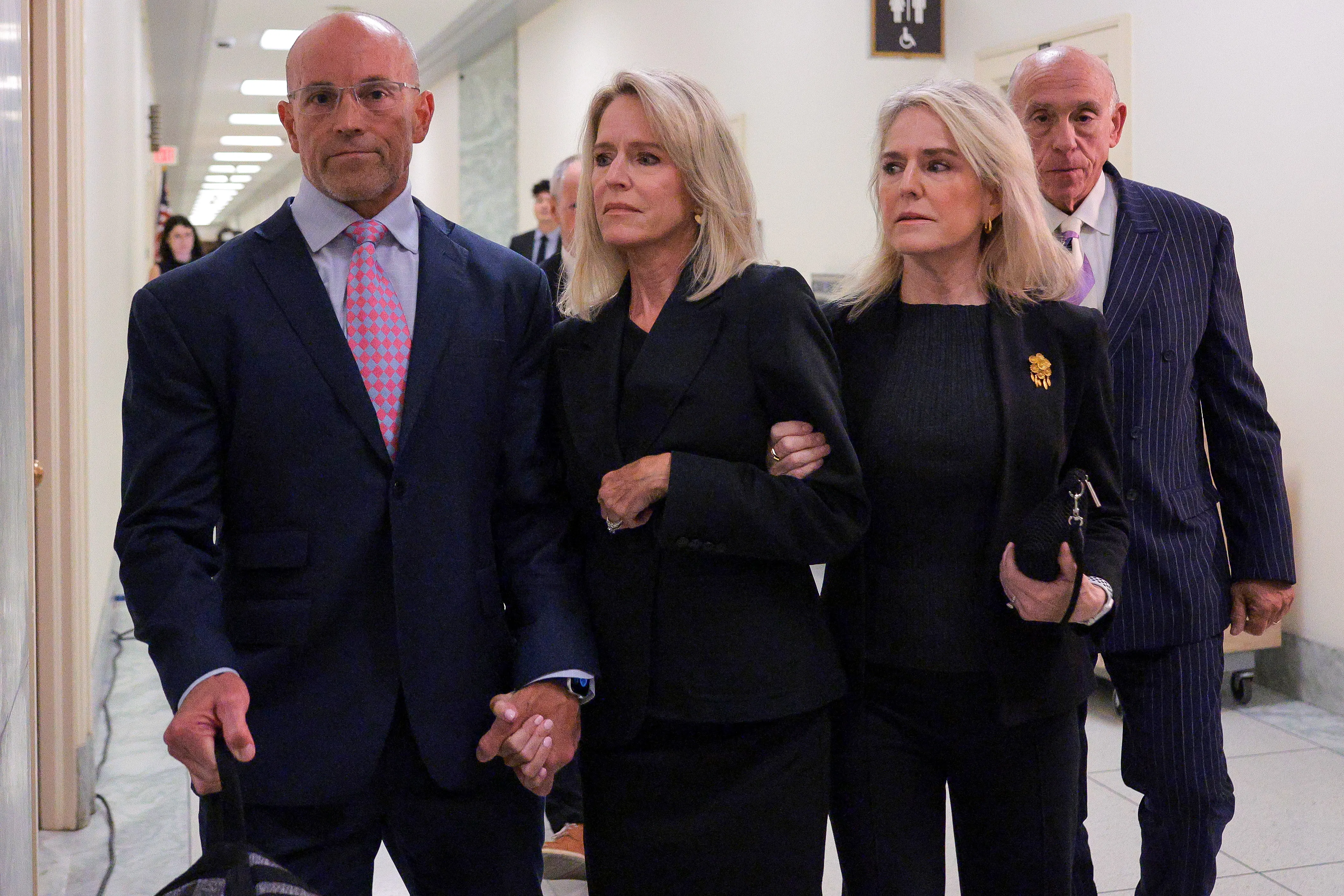 Lesley Groff walks while another woman holds her arm and a man holds her other hand.