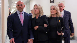 Lesley Groff walks while another woman holds her arm and a man holds her other hand.