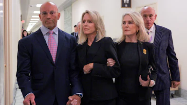 Lesley Groff walks while another woman holds her arm and a man holds her other hand.