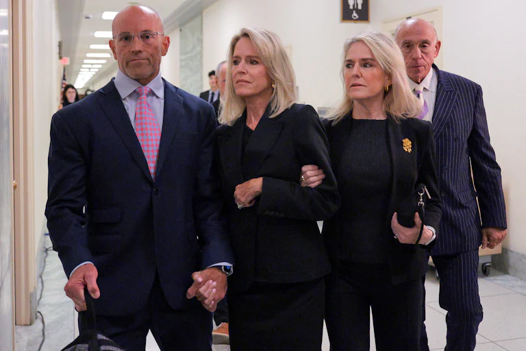 Lesley Groff walks while another woman holds her arm and a man holds her other hand.