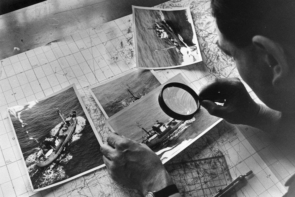 Examining photographs of a Soviet spy trawler taken during a reconnaissance flight over the Atlantic, 1968