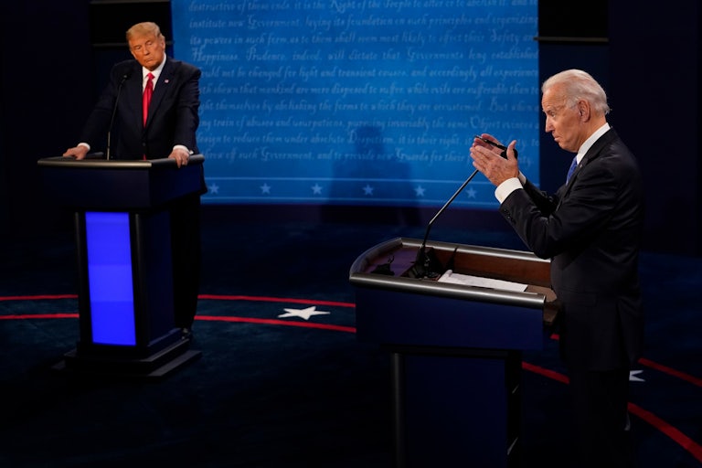 Donald Trump watches Joe Biden talk as they both stand at podiums
