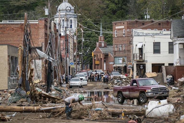 A downtown street is seen covered in wreckage with standing water in the streets.