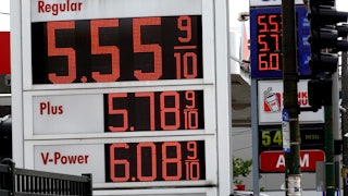 A sign displays gas prices, with "Regular" price being $5.55 9/10.