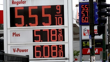 A sign displays gas prices, with "Regular" price being $5.55 9/10.