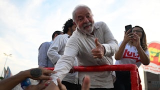 Luiz Inacio Lula da Silva reaches down to shake supporters' hands.
