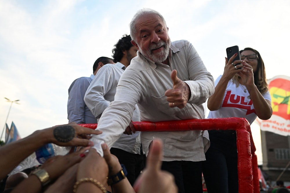 Luiz Inacio Lula da Silva reaches down to shake supporters' hands.