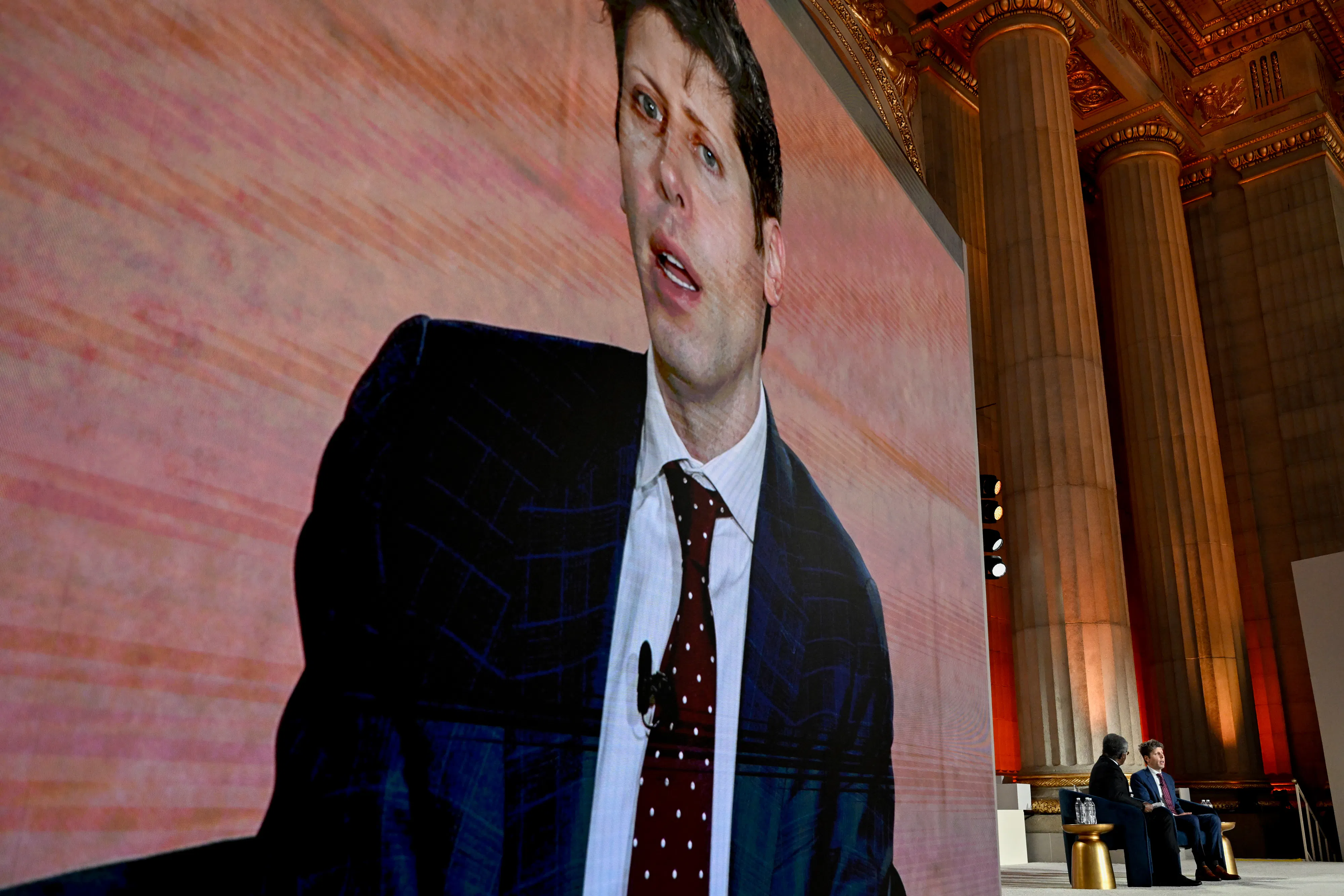 On March 11, Sam Altman, the CEO of OpenAI, spoke at BlackRock’s 2026 Infrastructure Summit in Washington, D.C. Altman's face looms on a screen while he sits onstage.  