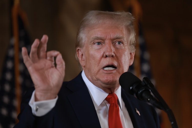 Donald Trump speaks at a mic and makes a hand gesture