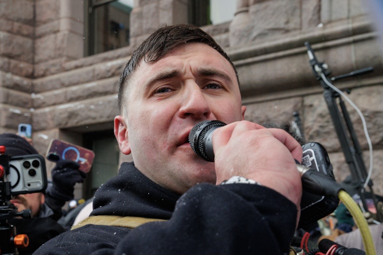 Jake Lang speaks into a microphone while outdoors.