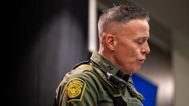 CBP Commander Gregory Bovino purses his lips and looks down during a press conference