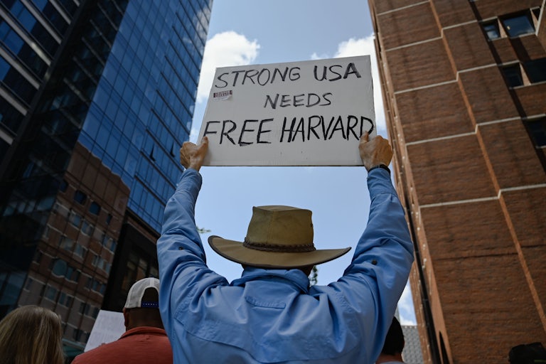 A protester holds a sign that reads "Strong USA Needs Free Harvard."
