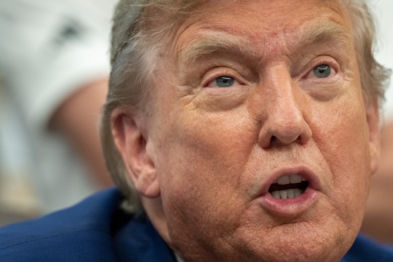 Donald Trump speaks while sitting at his desk in the Oval Office