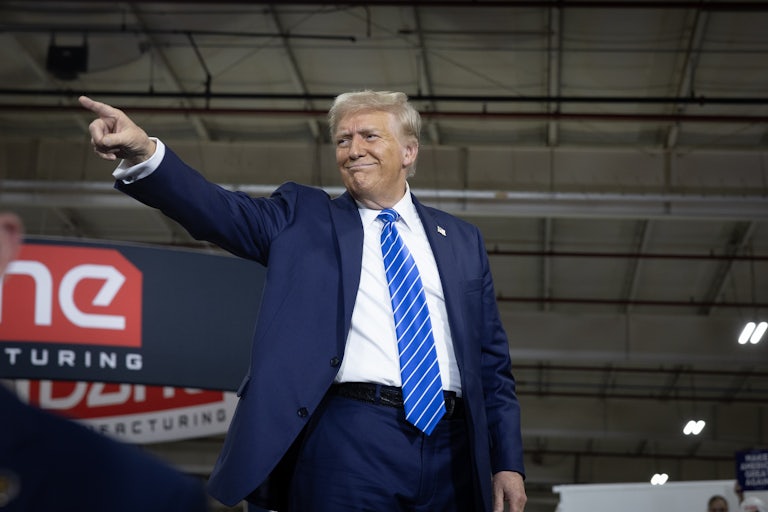 Donald Trump smiles and points at a campaign stop