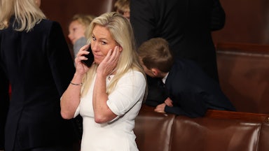 Marjorie Taylor Greene makes a face as she speaks on the phone while standing in the Capitol.