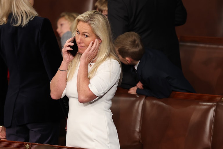 Marjorie Taylor Greene makes a face as she speaks on the phone while standing in the Capitol.