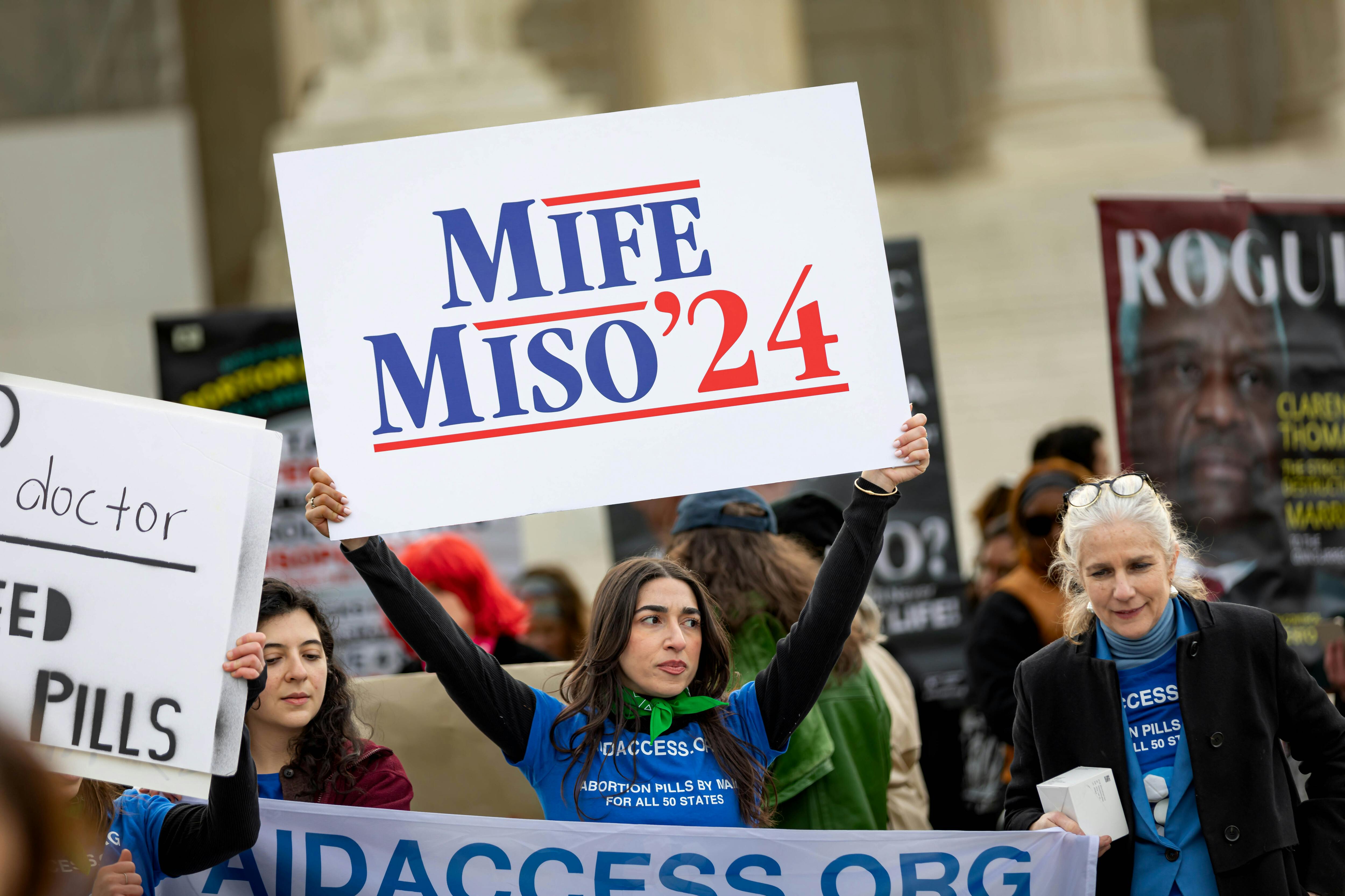 Demonstrators hold signs including one reading "Mife Miso '24"