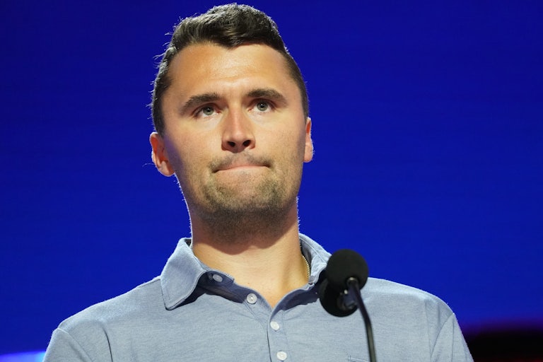 Charlie Kirk frowns while standing in front of a microphone