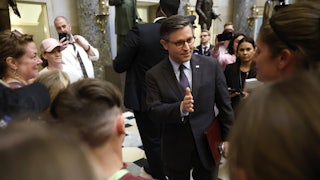 Mike Johnson stands in a group of people and gestures while talking.