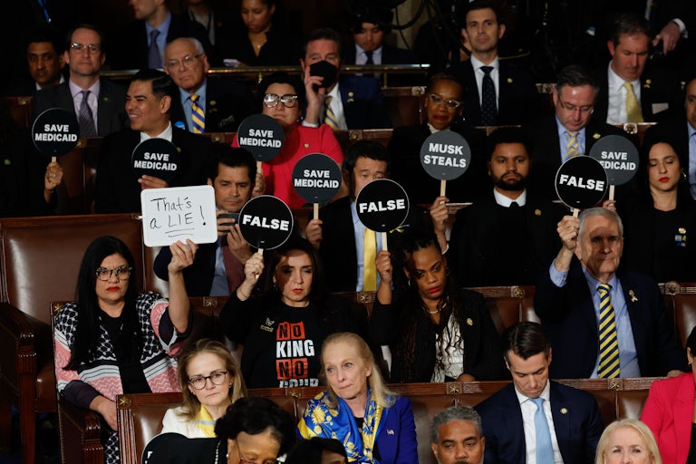 Democratic members of Congress hold up signs during Donald Trump’s address to a joint session