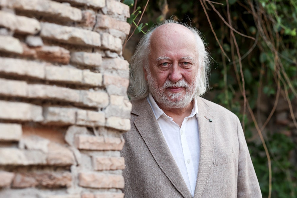 writer Laszlo Krasznahorkai stands behind a brick wall